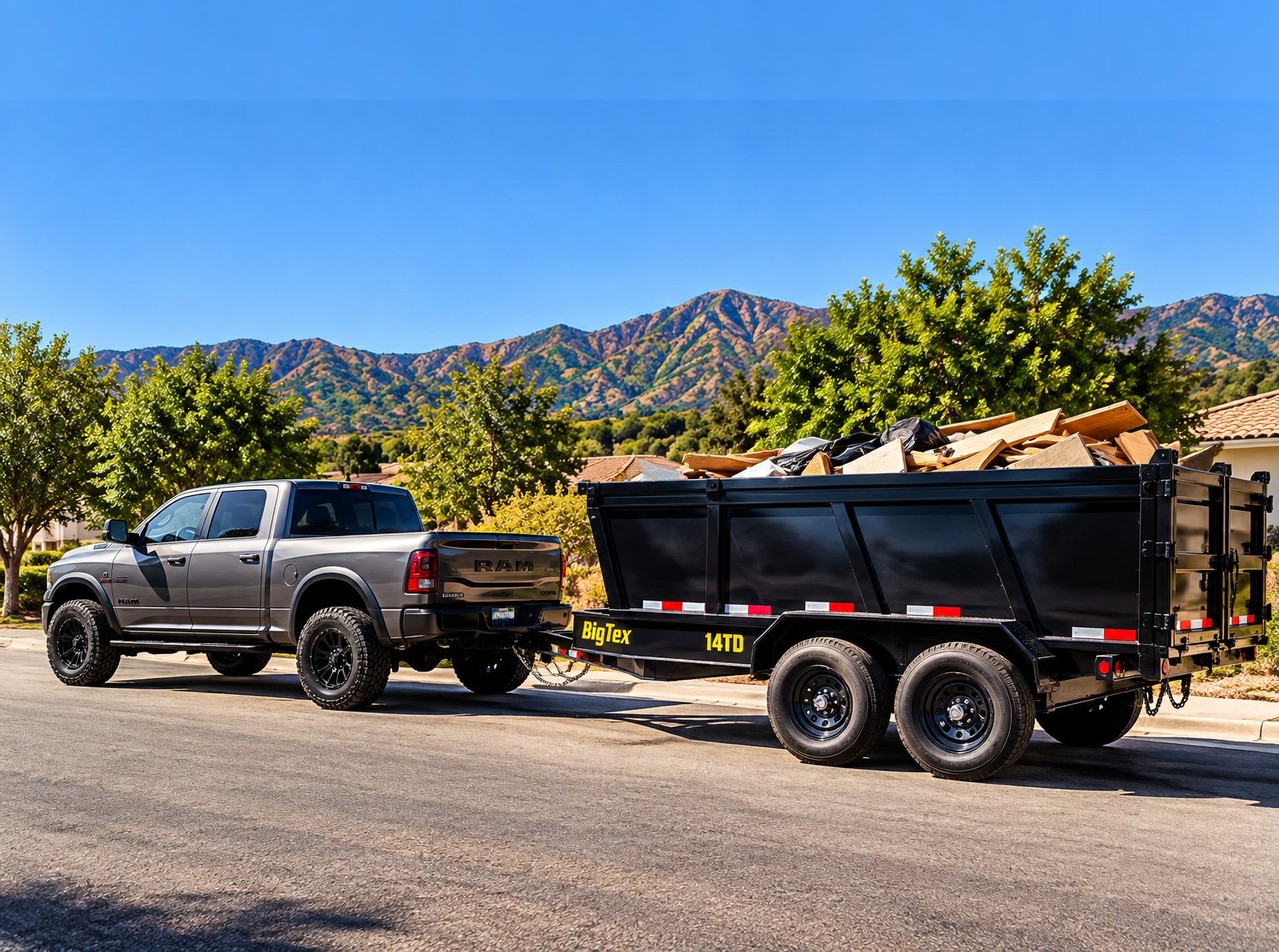 Gray Ram truck with the black 14-foot Big Tex dump trailer on a residential street